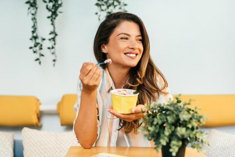 Mulher comendo iogurte, lanche saudável - iStock - iStock