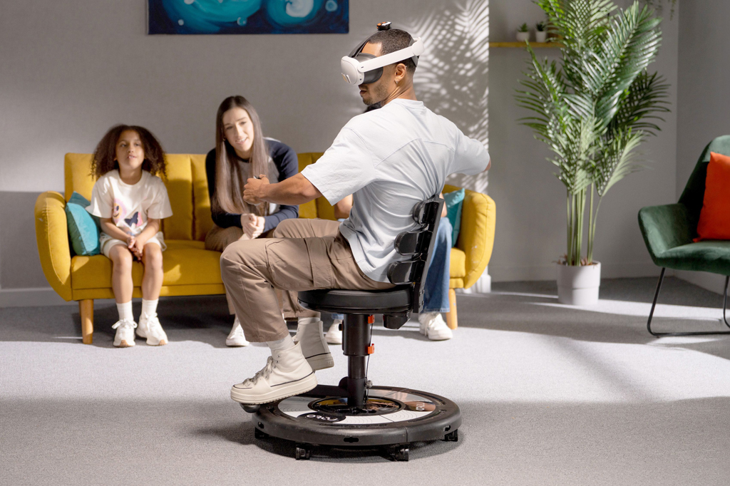 Si_468_Tech_Cadeira_Rotovr Imagem de rapaz utilizando a cadeira Roto VR e capacete de realidade virtual Quest, sendo observado três pessoas.