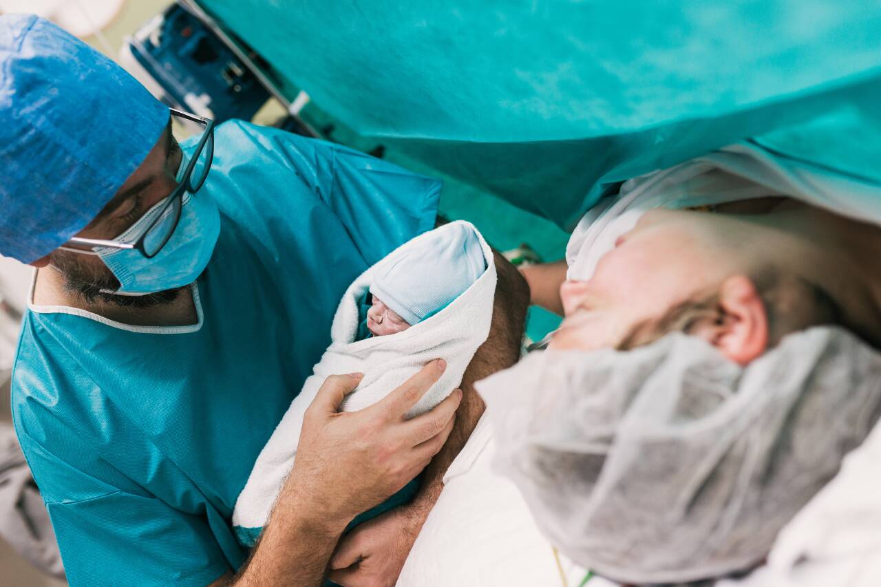 Médico segurando bebê recém-nascido após parto.