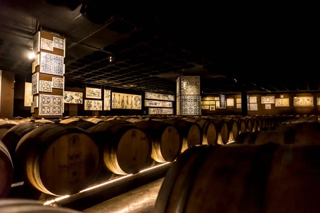 Sala com barris de madeira para envelhecer o vinho e, nas paredes, grandes paineis de azulejos ibericos