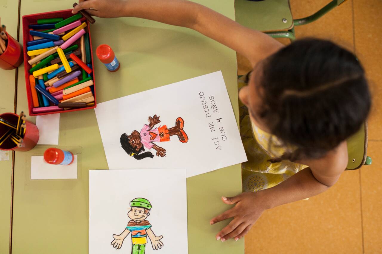Criança desenhando com lápis coloridos em mesa