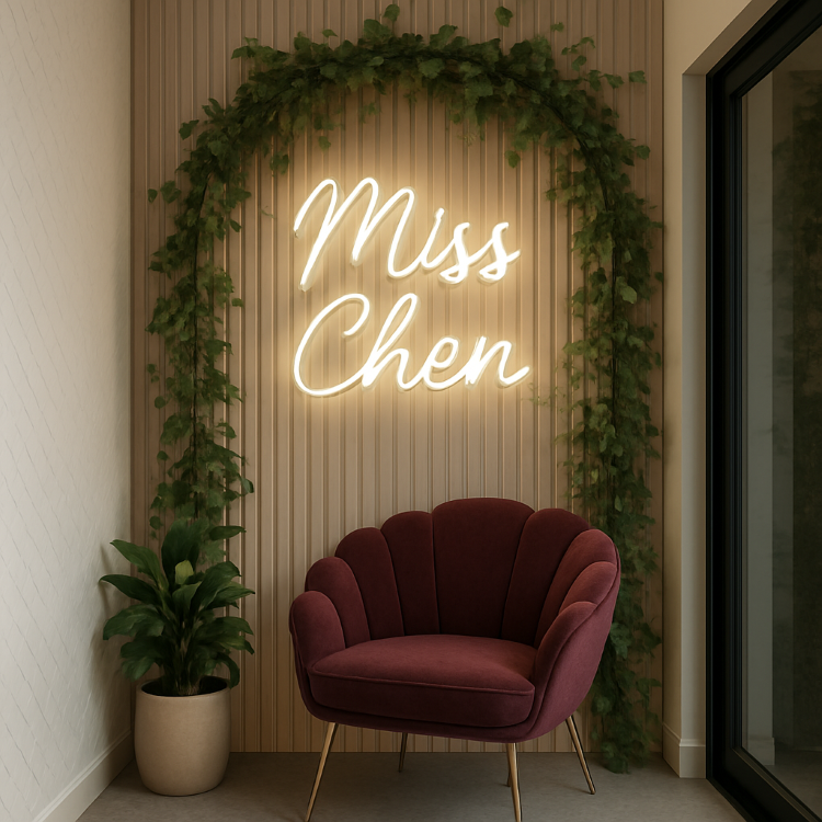 Uma luminária de neon branco com a frase "Miss Chen" em uma parede de ripas de madeira. Acima, um arco de hera e, em frente, uma poltrona de veludo bordô em formato de concha com pés dourados.
