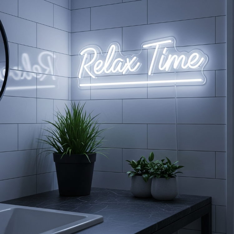 Um letreiro de neon branco com a frase "Relax Time" sobre uma parede de azulejos brancos. Abaixo, há um balcão de mármore com duas plantas em vasos escuros, uma grande e uma dupla menor.