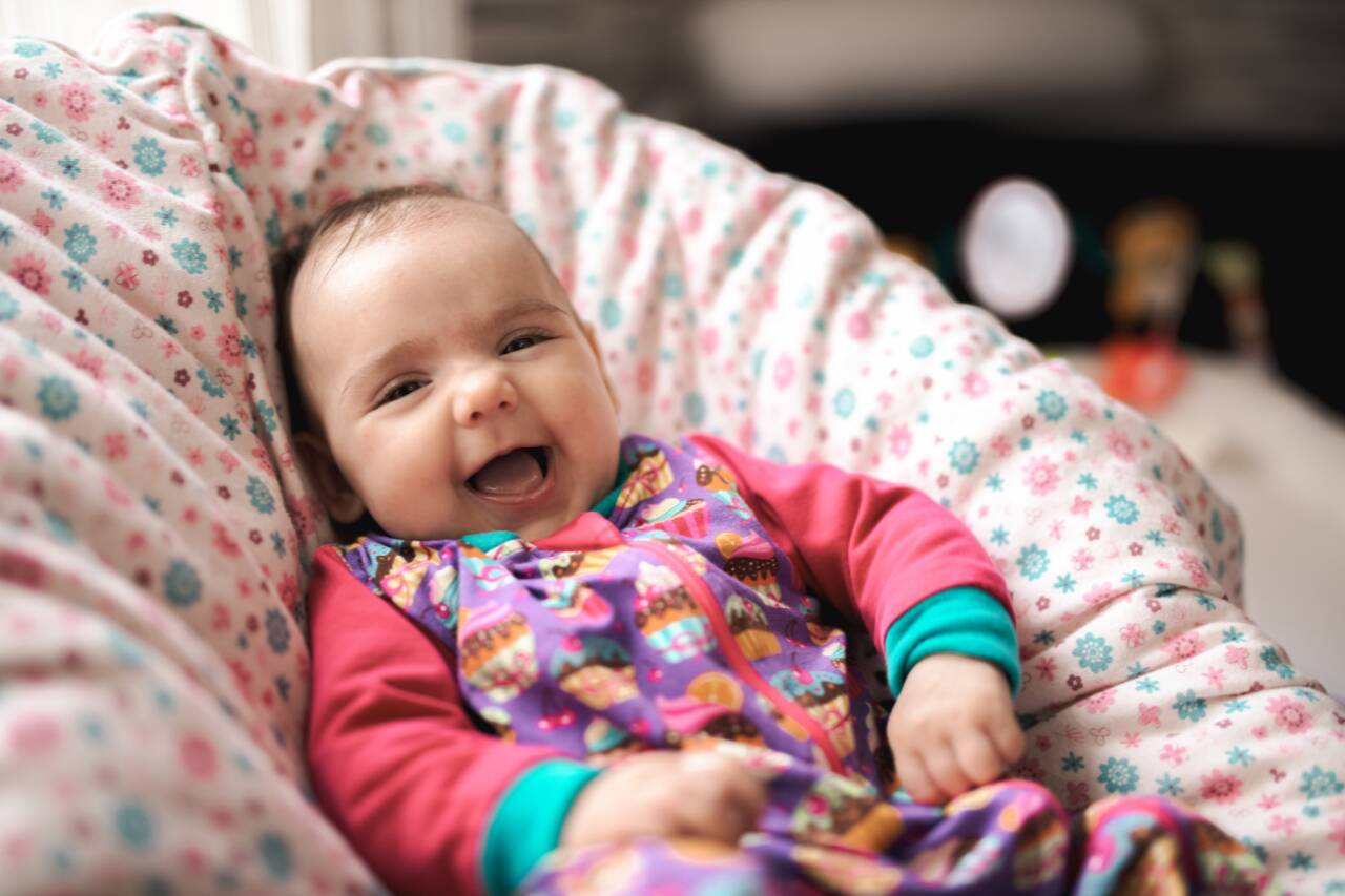 Bebê sorrindo em um sofá colorido