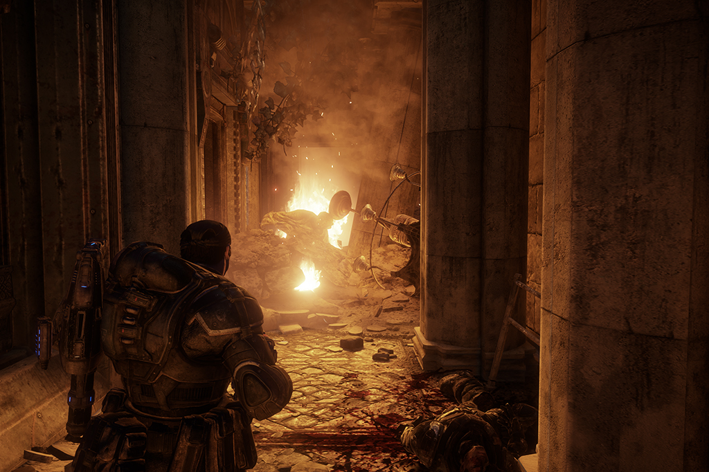 2608-Gears-Layout_Site2 Fotografia das cenas do jogo Gears od War - Reloaded, um soldado passando por ruínas que estão pergaqndo fogo.