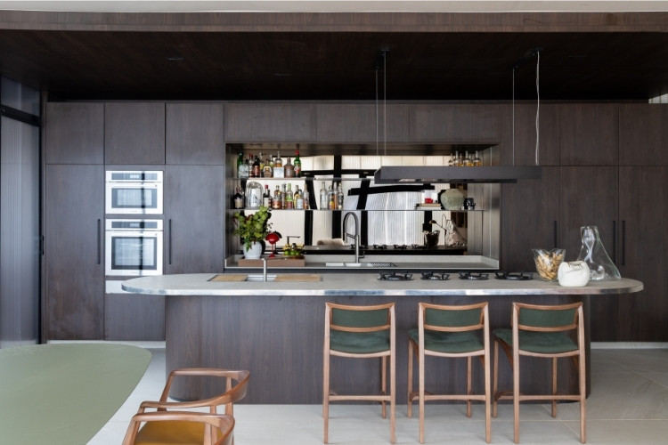 Cozinha moderna decorada com móveis de madeira escura e bancada de inox oval