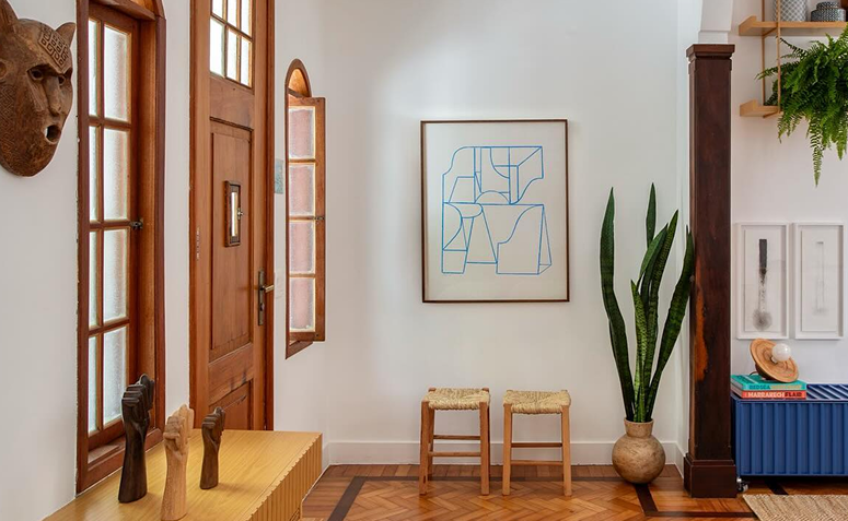Hall de entrada com porta de madeira, plantas em vaso e decoração minimalista, representando o significado da entrada no feng shui.
