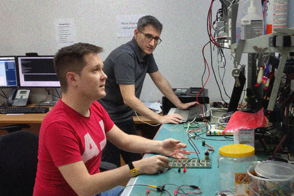 Fotografia do Luigi Calligaris e o engenheiro eletrônico Carlos Dell’Aquila testando placas OpenIPMC no laboratório de instrumentação científica do SPRACE.