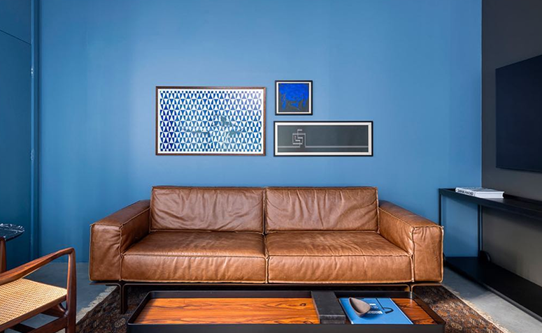 parede pintada com azul escuro atrás de sofá de couro marrom.