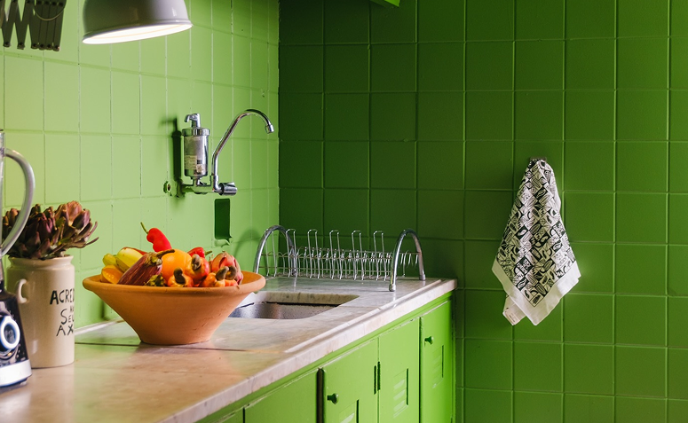 Cozinha simples com azulejos e armários pintados de verde.