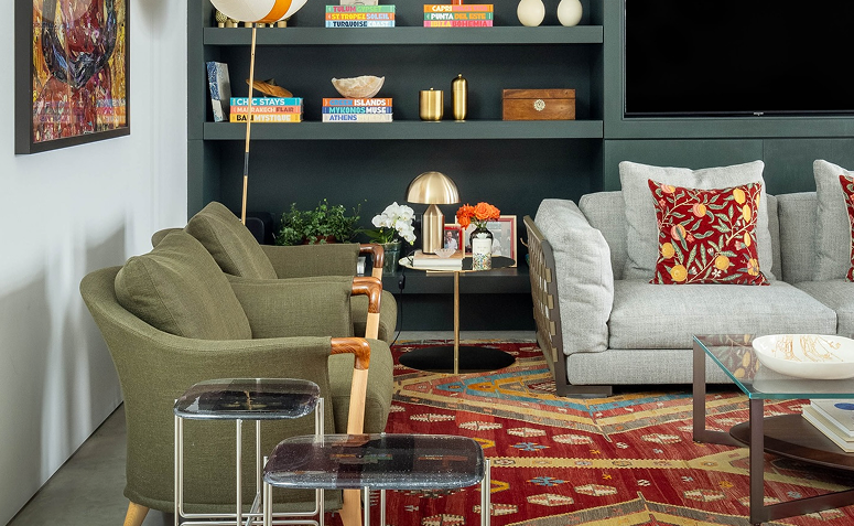 estante verde-esmeralda e sofá neutro com almofadas coloridas em ambiente maximalista.