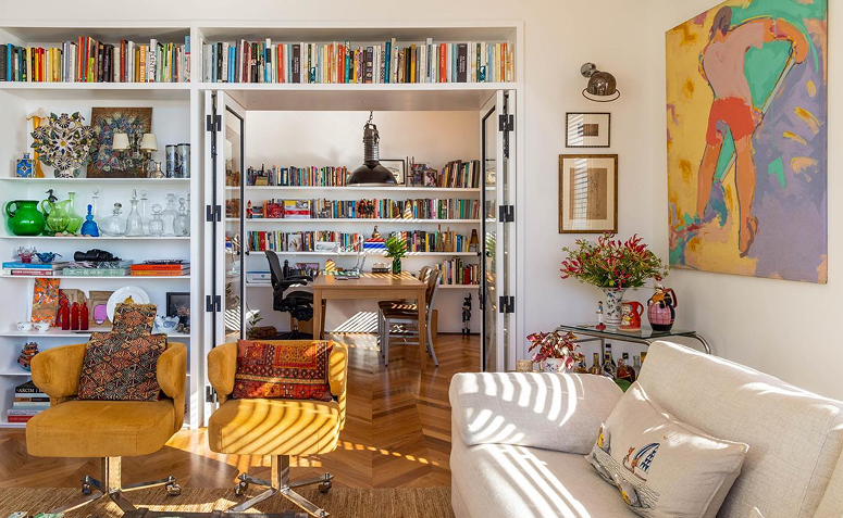 estante com livros, lembranças de viagem e objetos antigos na decoração.