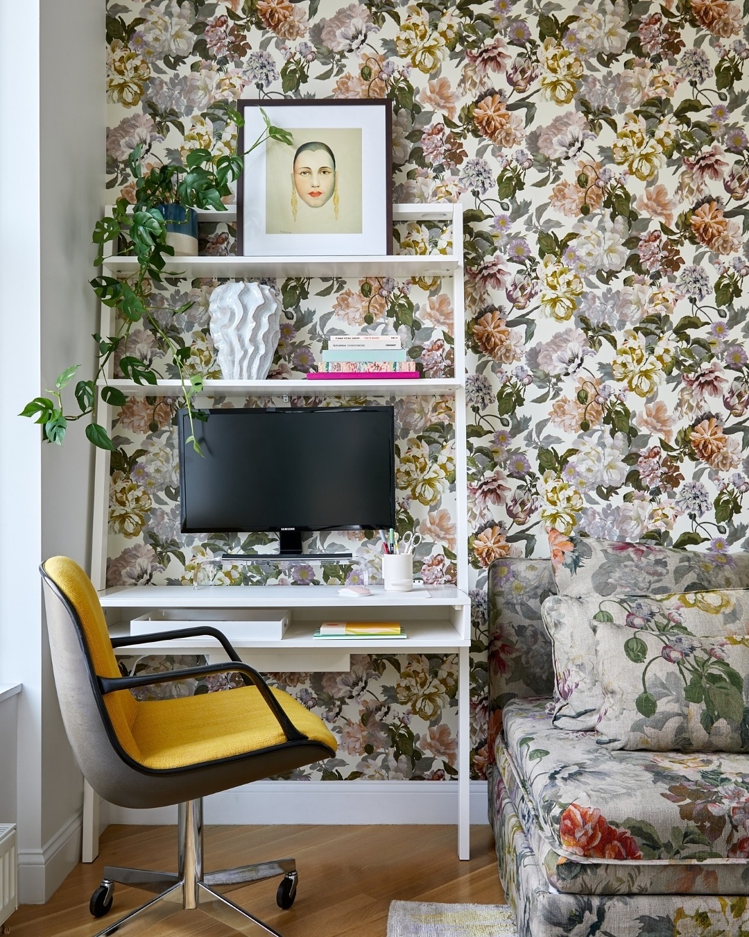 espaço de trabalho com papel de parede estampado e quadros coloridos.