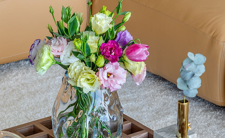 Arranjo com lisianthus em vaso transparente na mesa de centro.