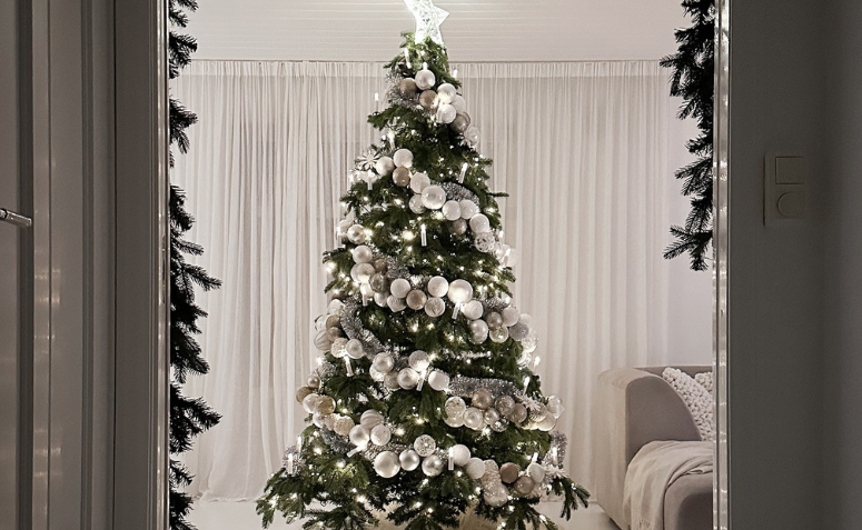 Árvore de Natal decorada com bolas brancas e luzes suaves em ambiente minimalista no estilo escandinavo