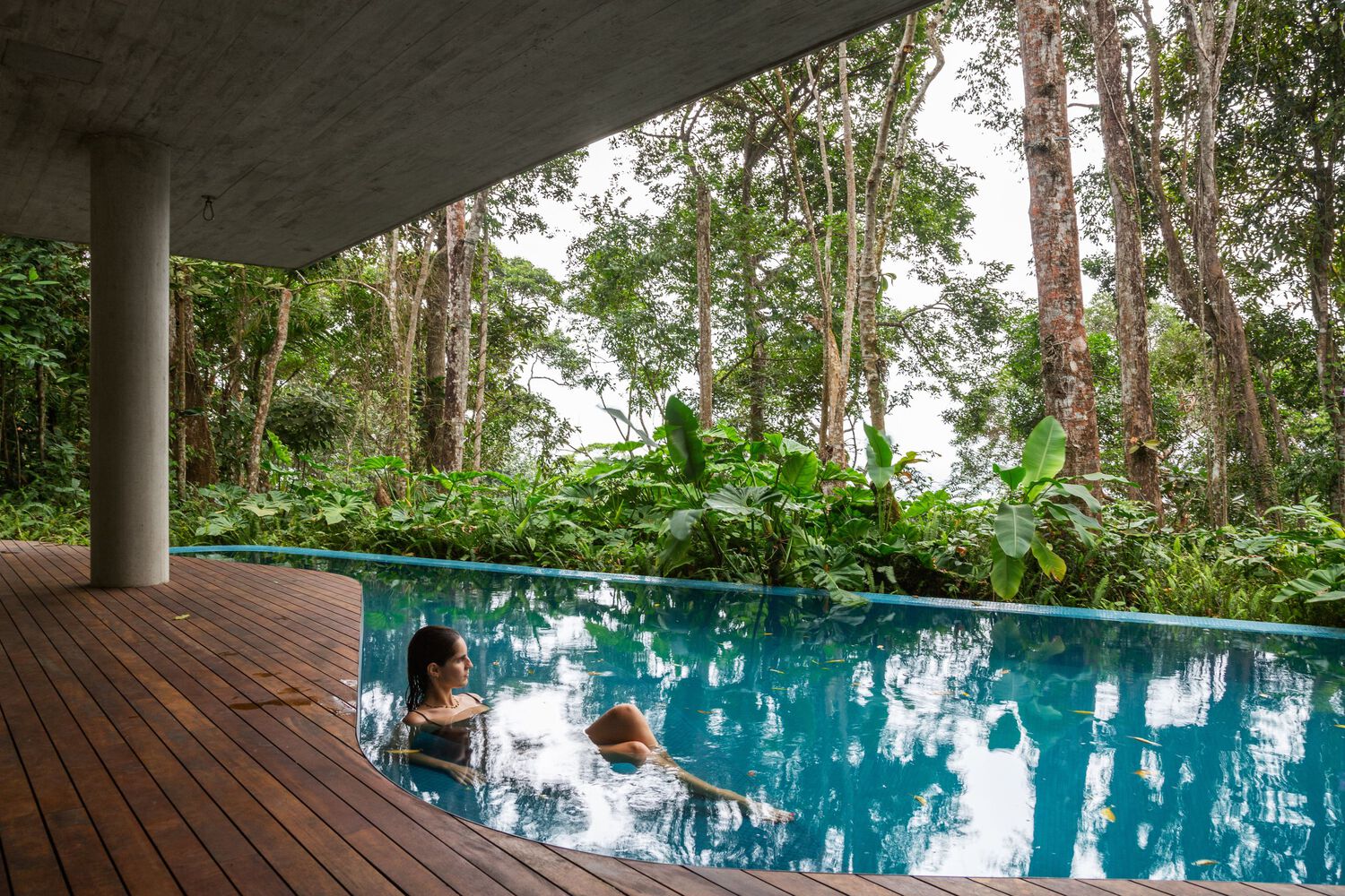 Deck de madeira e piscina da Casa Azul se estendendo em direção à floresta e ao mar.