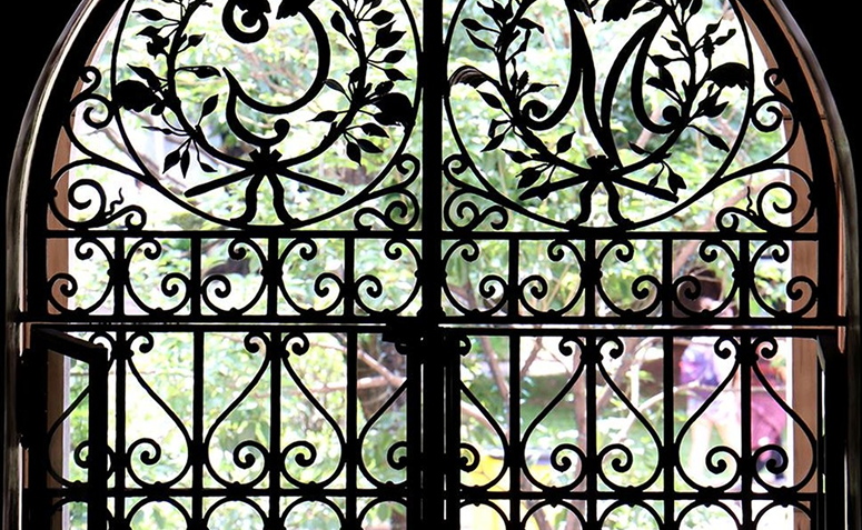 portão feito em ferro fundido com adornos e ornamentos de origem africana, como a representação do Ideograma Sankofa, que pertence ao conjunto de símbolos gráficos Adinkra, de origem dos povos Akan.