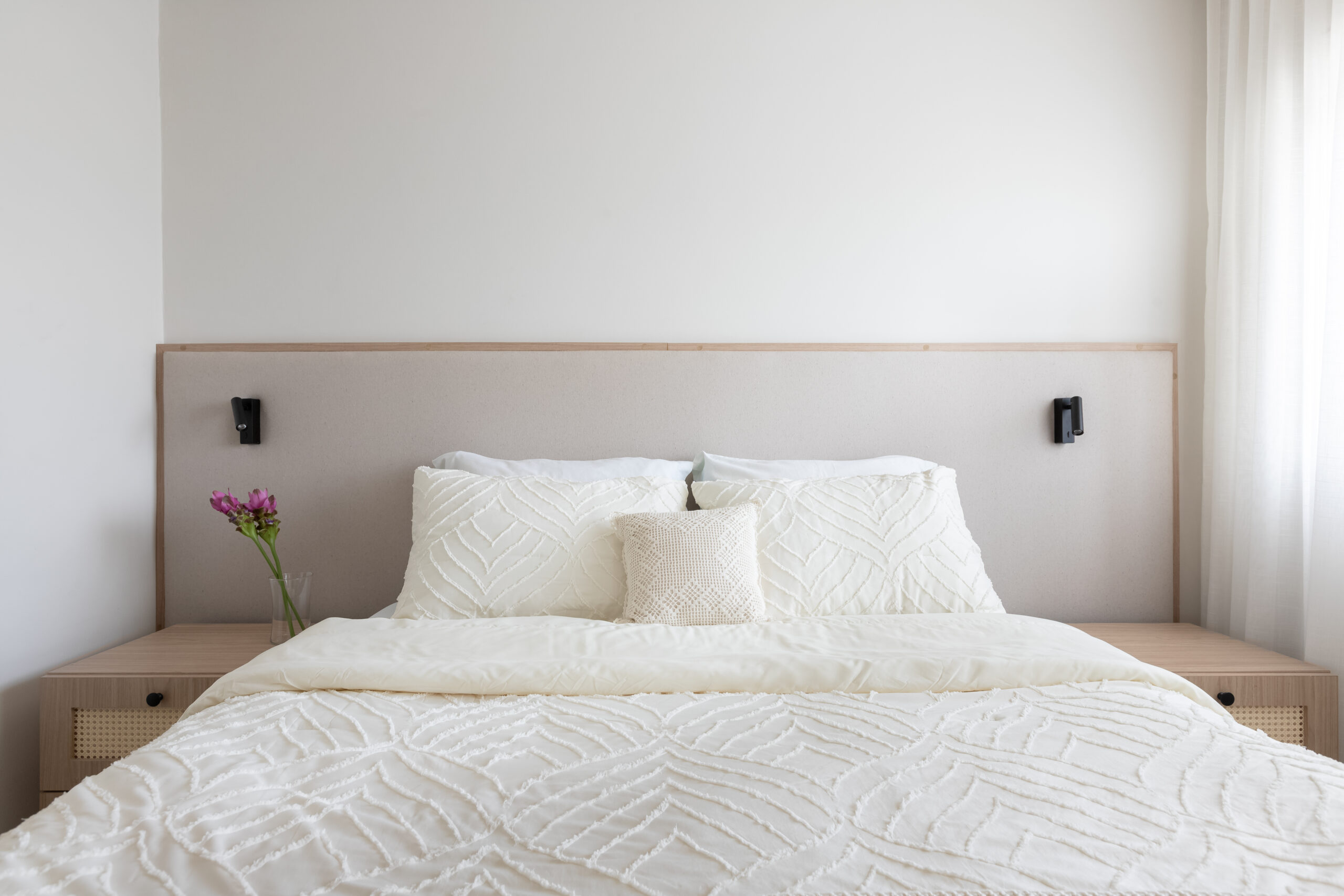 quarto com cabeceira neutra e almofada de crochê artesanal.