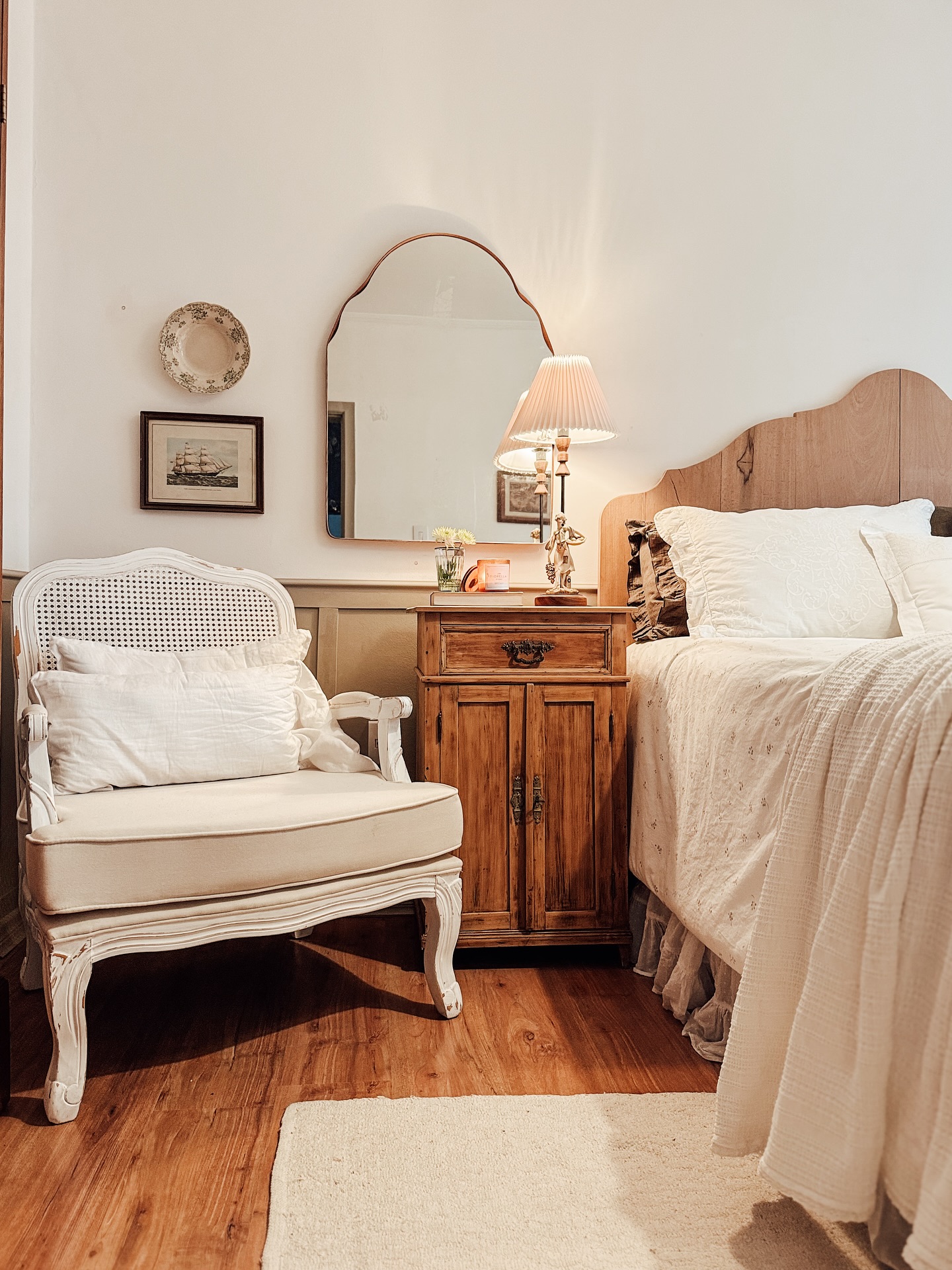 Quarto estilo farmhouse com móveis de madeira, tons neutros e poltrona branca.