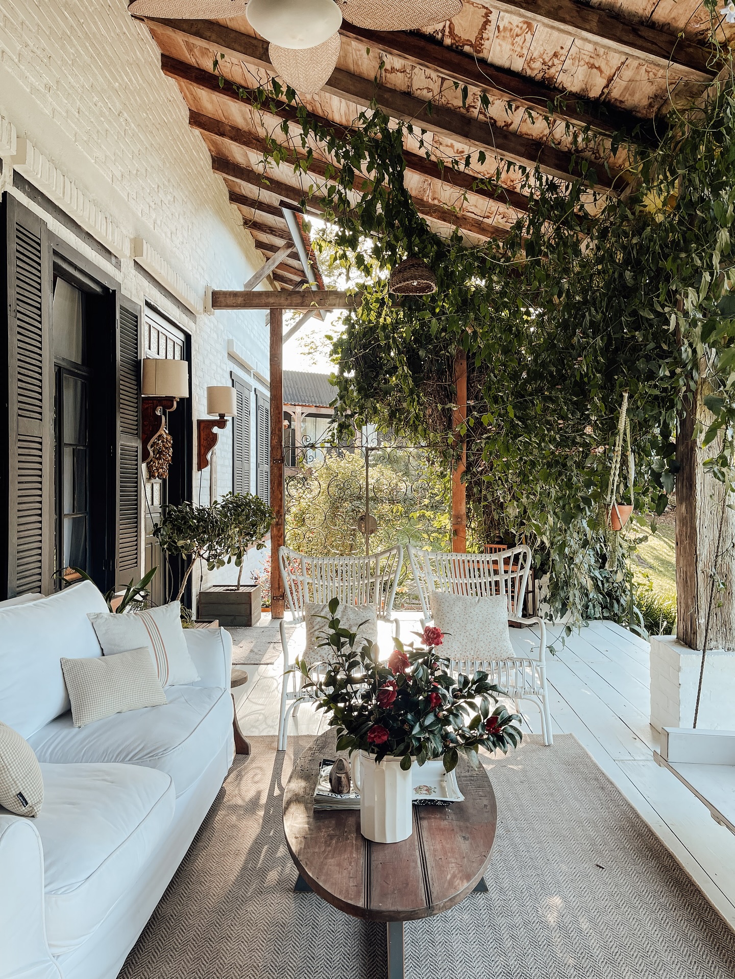 Decoração de varanda farmhouse com móveis de madeira, vegetação e atmosfera acolhedora.
