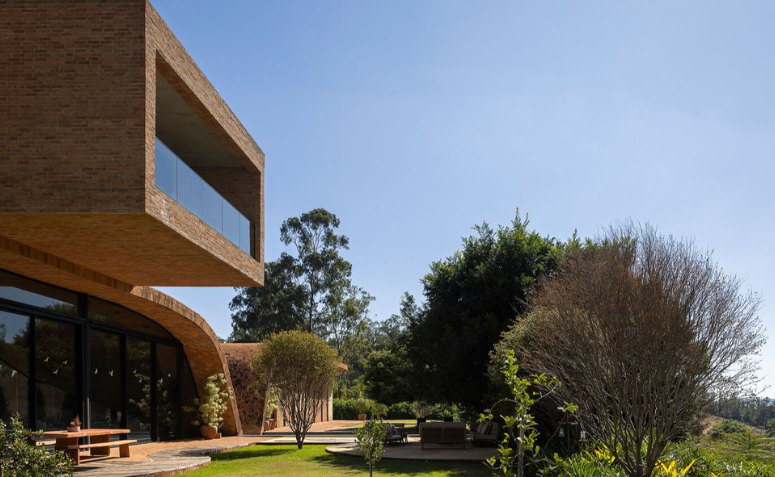 Vista externa da Passive House com vegetação nativa ao redor da fachada.