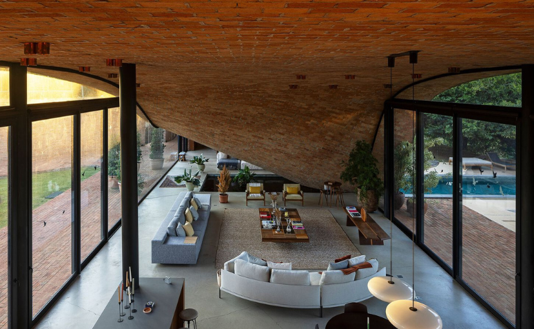 Sala interna da Passive House com ambientes integrados e grandes esquadrias de vidro.