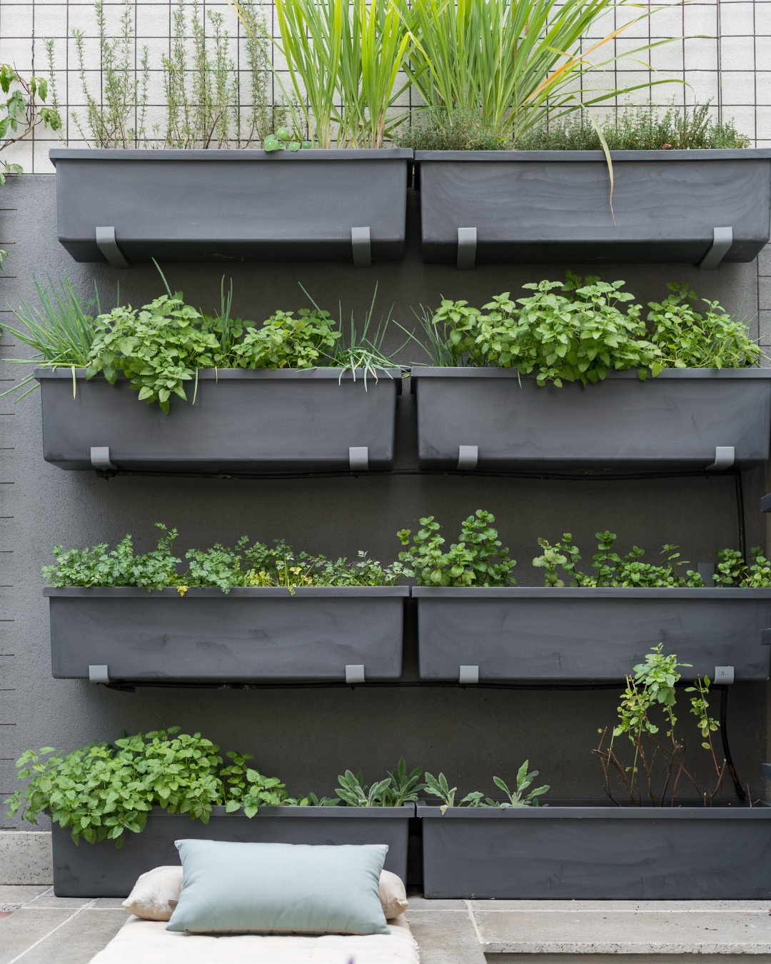 horta vertical de com vasos de ervas e temperos em varanda pequena.