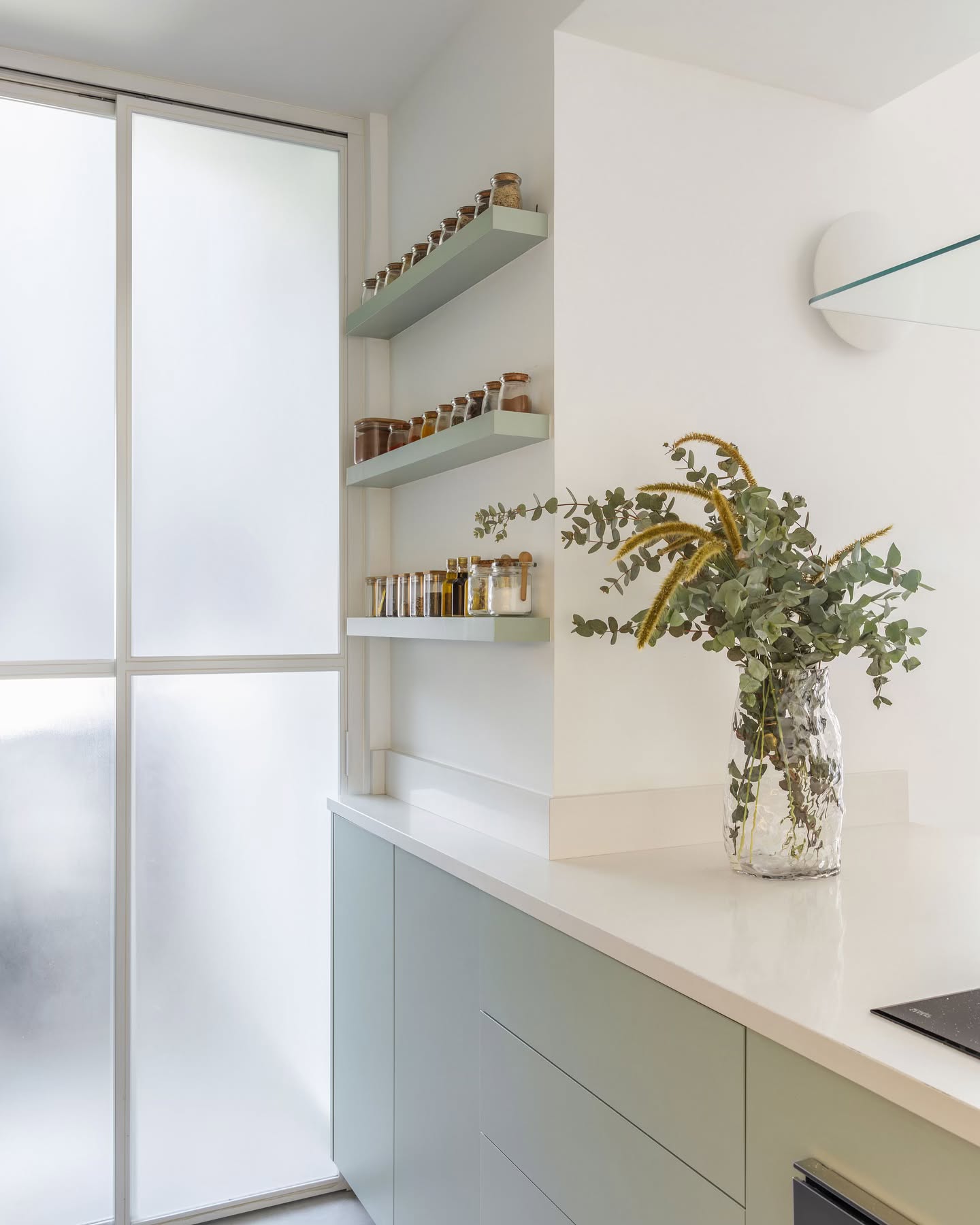 Prateleiras estreitas instaladas na parede da cozinha com potes de temperos organizados lado a lado, unindo praticidade e estilo ao ambiente.