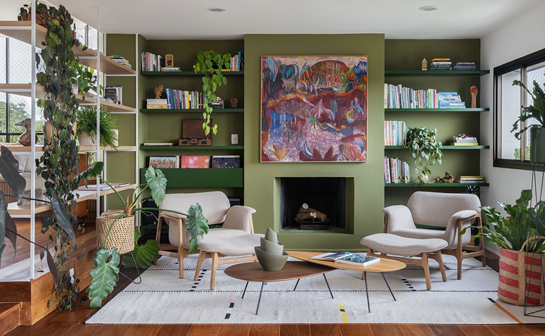 Sala com muitas plantas e estante verde decorada, criando atmosfera de vitalidade e abundância.