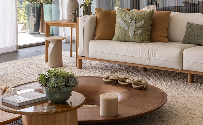 Detalhe de sala com mesa decorada com vela e plantas, transmitindo clima acolhedor e renovado.