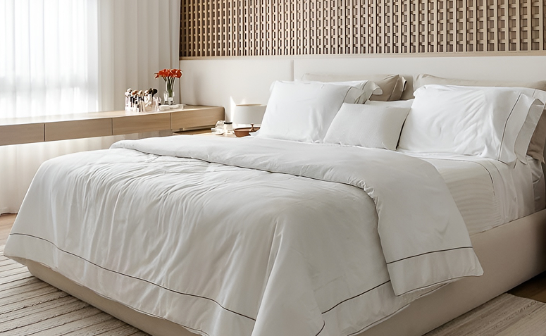 Cama estilo hotel com enxoval branco, várias camadas de roupa de cama e travesseiros fofos, transmitindo conforto.