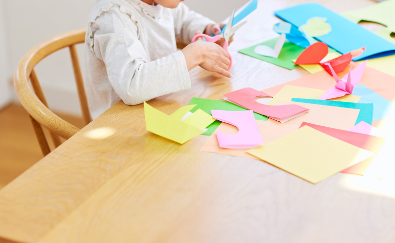 criança fazendo artesanato com dobraduras de papel e origamis