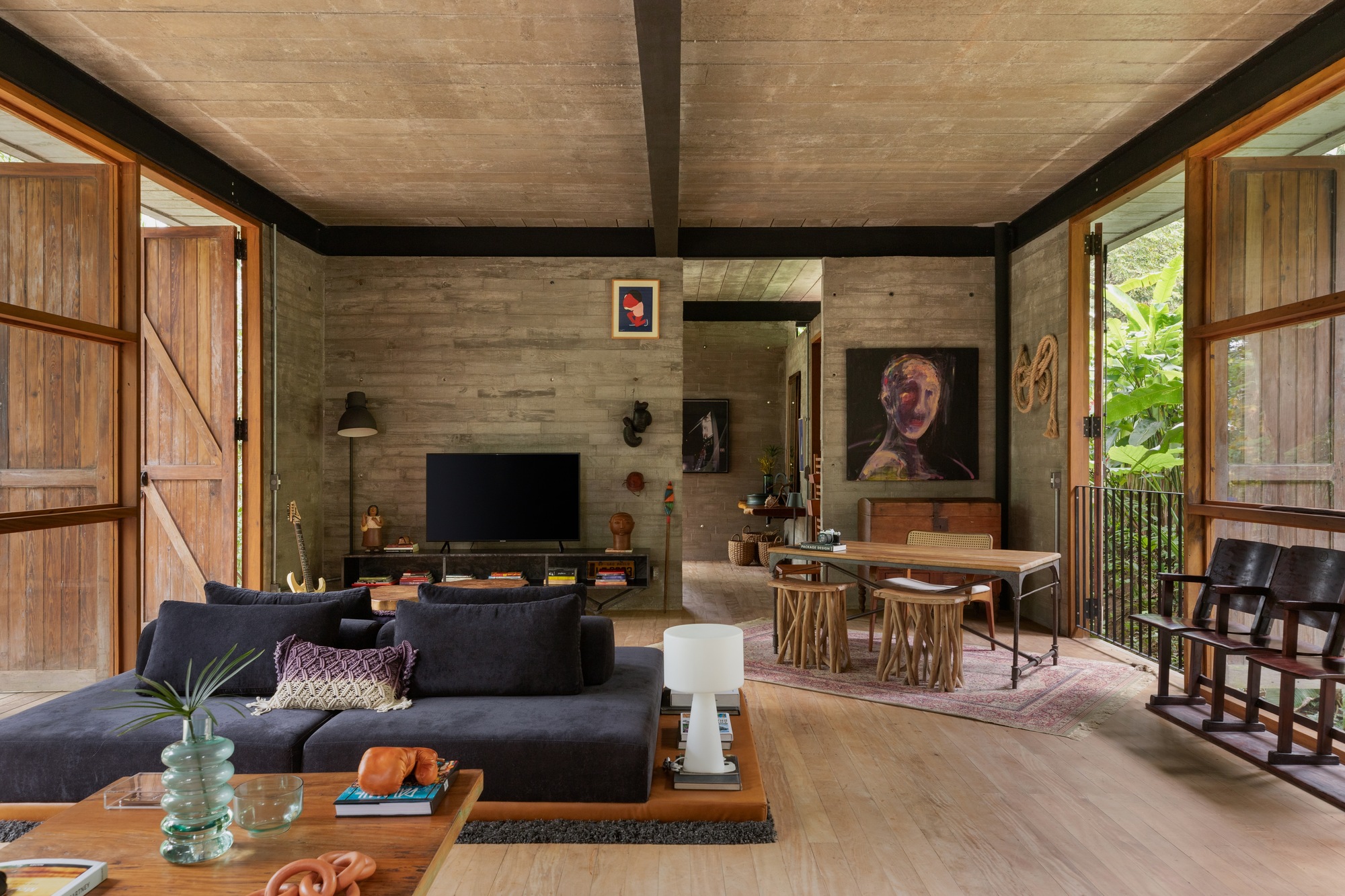 sala com portas de demolição em madeira, paredes de concreto e elementos garimpados.