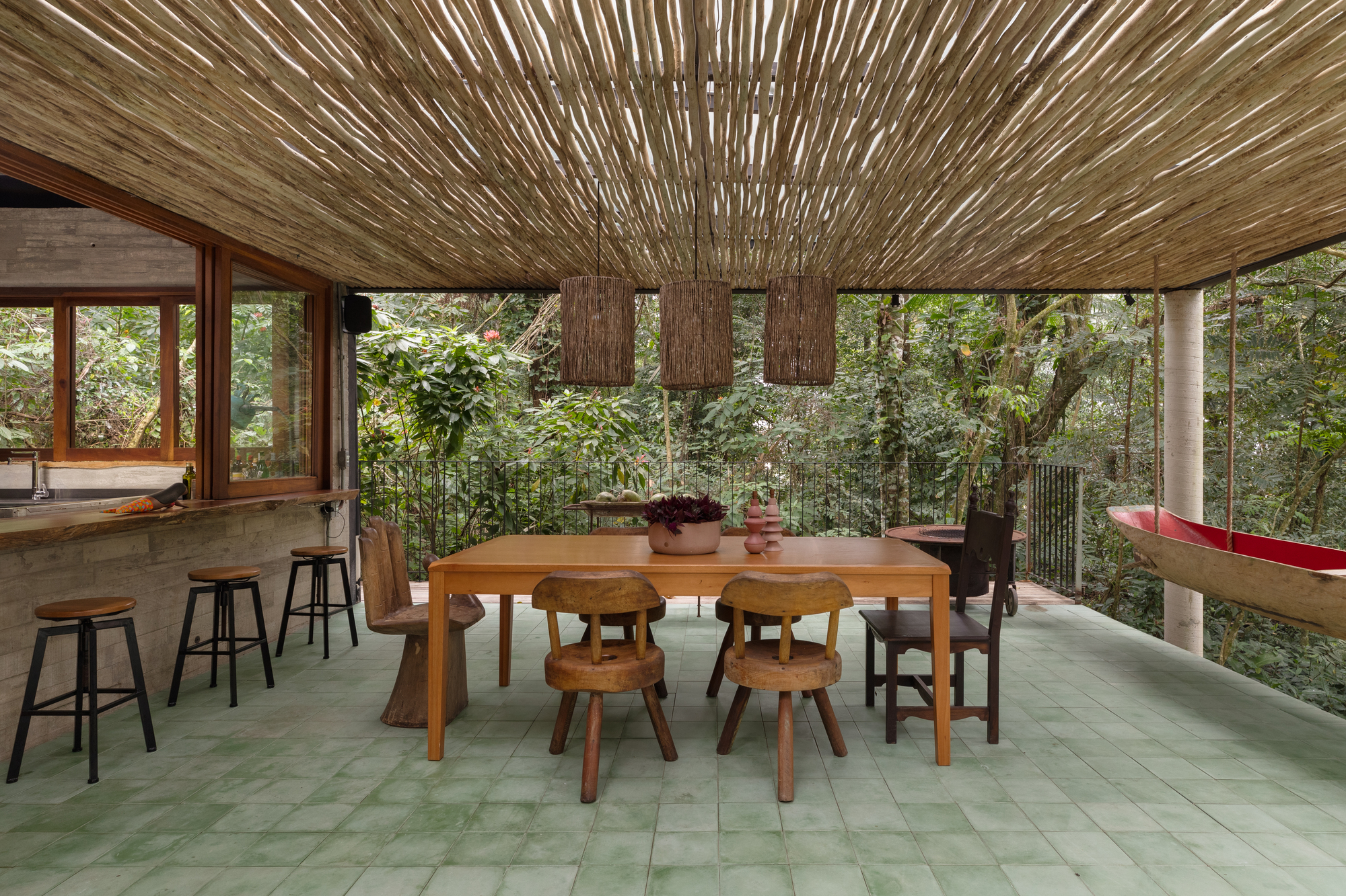 Varanda suspensa com canoa de pescador transformada em bar e redes voltadas para as árvores.