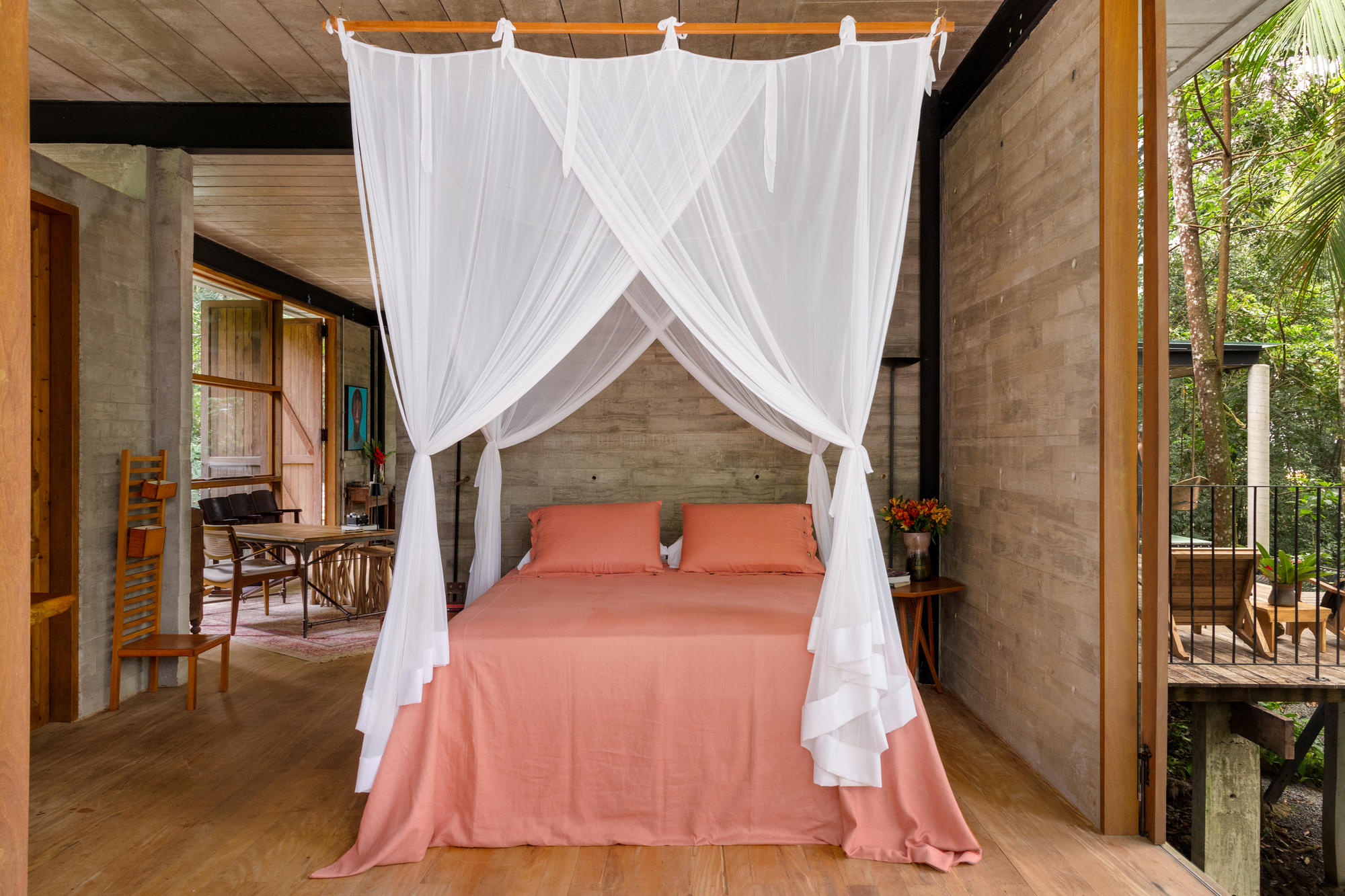 Suíte com piso de madeira, portas amplas e vista direta para a Mata Atlântica.