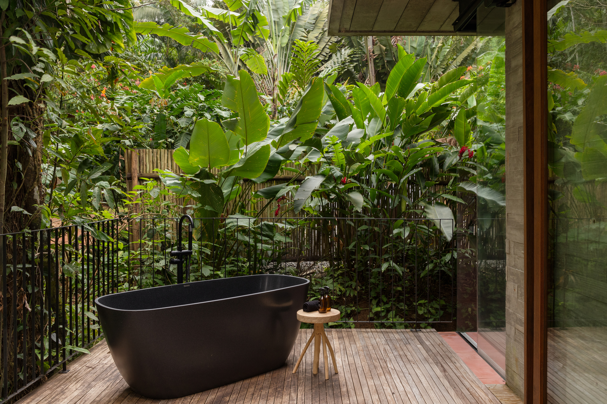 Deck spa suspenso com banheira externa entre as árvores, em meio à Mata Atlântica.