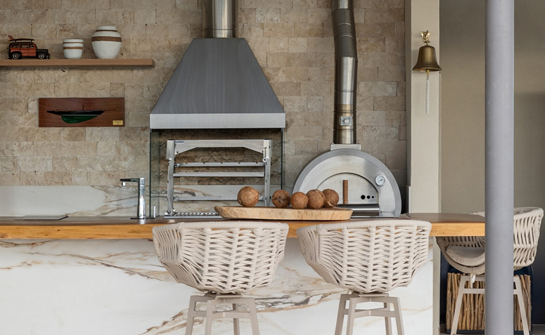 Churrasqueira moderna com grelha metálica e coifa inox em área gourmet, ilustrando cuidados com limpeza