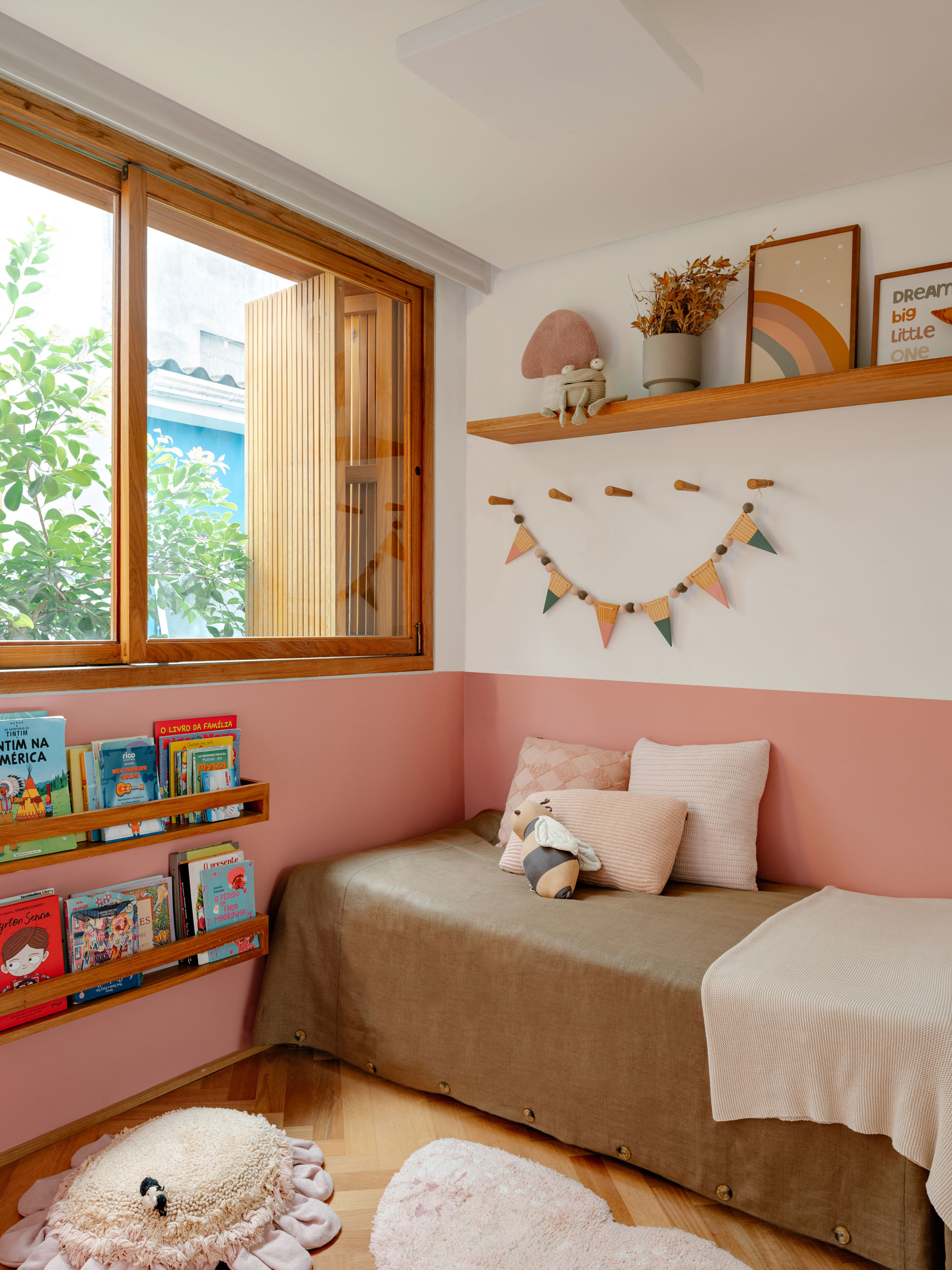 Quarto do bebê da Casa MA com grande caixilho de venezianas ripadas e vista para a copa do araçá no jardim interno.