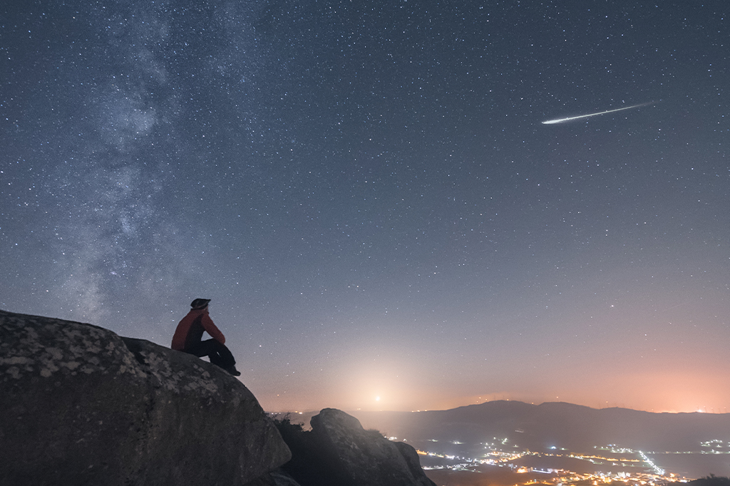 3010–Calendário-Astronômico-Layout_Site Um homem observando uma estrela cadente.
