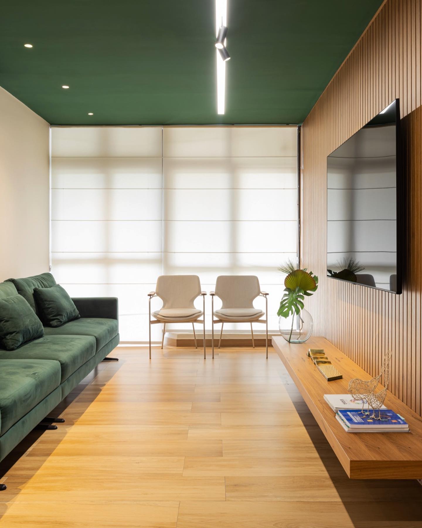 Sala com teto verde escuro, paredes claras e mobiliário em tons neutros, mostrando como o teto escuro cria profundidade e elegância no ambiente.