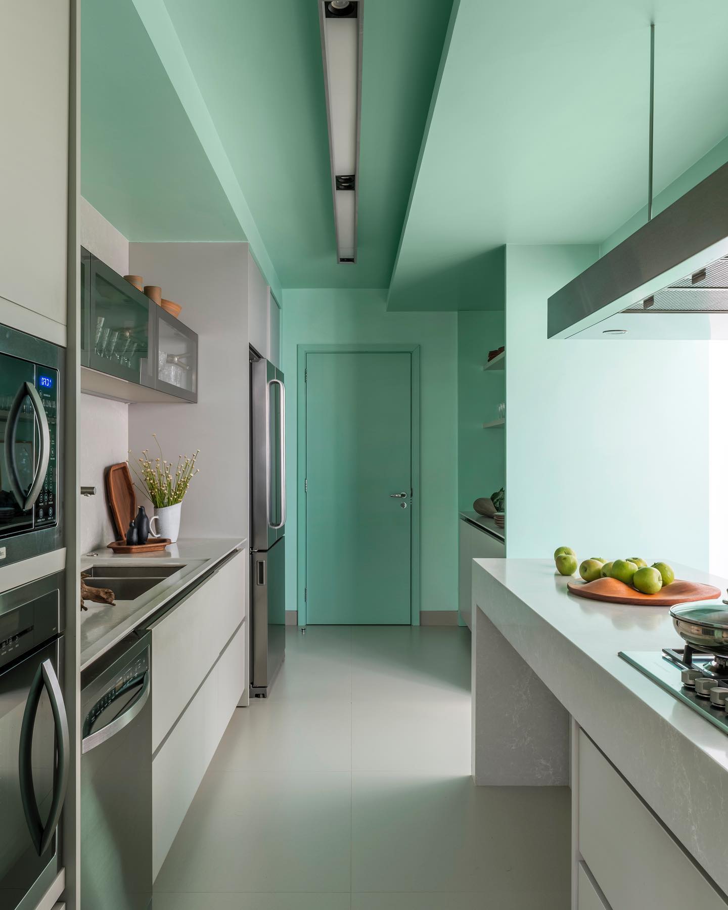 Cozinha moderna com teto pintado em verde formando uma faixa contínua que desce pelas paredes e destaca a arquitetura do ambiente.