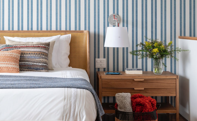 quarto com decoração náutica, papel de parede com listras azuis e madeira e rattan