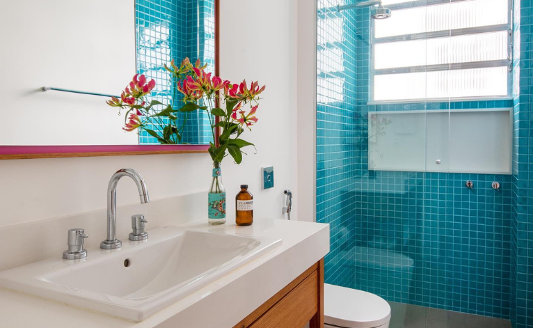 banheiro com decoração náutica, uso de azulejo azul e toques de vermelho e madeira