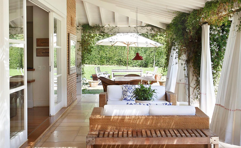 varanda com cortinas e ombrelone para diminuir a incidência de sol no verão