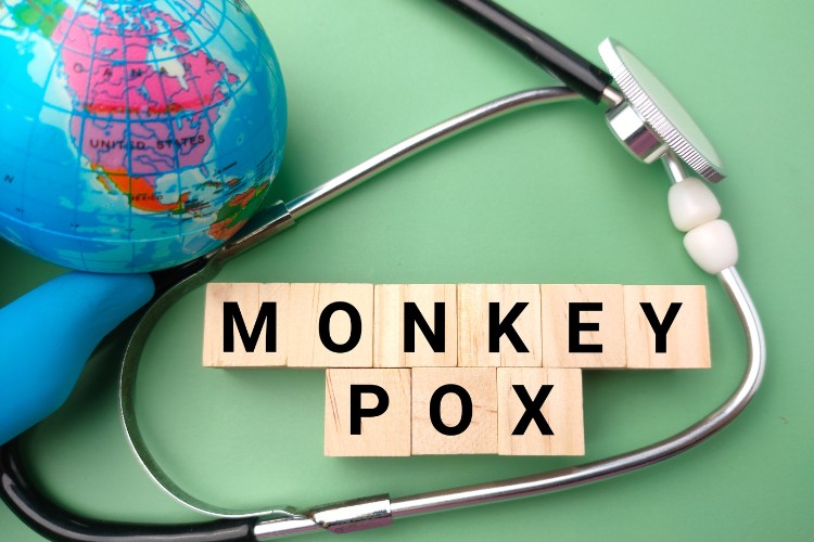 Mpox-1 Foto de fundo verde com globo terrestre, estetoscópio e "Monkey pox" escrito com peças de palavra cruzada