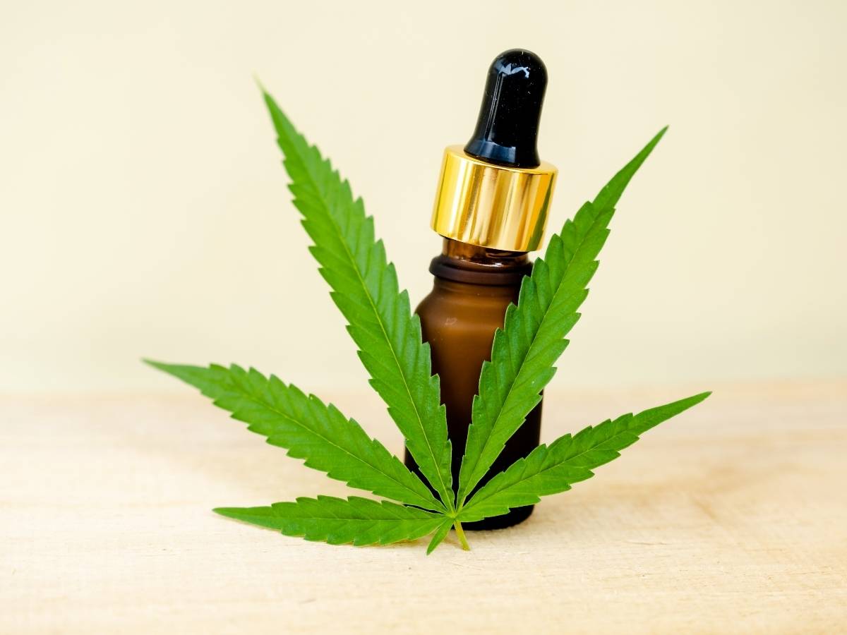 Canabidiol Vidro de óleo de canabidiol atrás de uma folha de maconha.