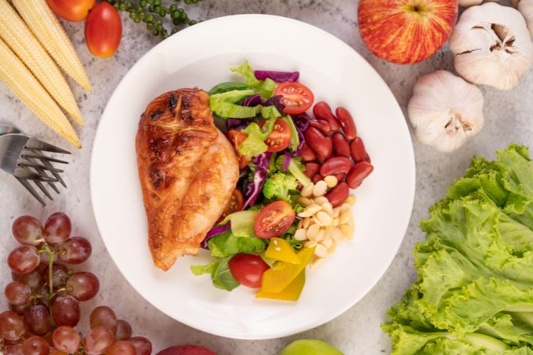 O-Que-Comer-No-Verao Prato com filé de frango, legumes, salada, leguminosas e oleaginosas.