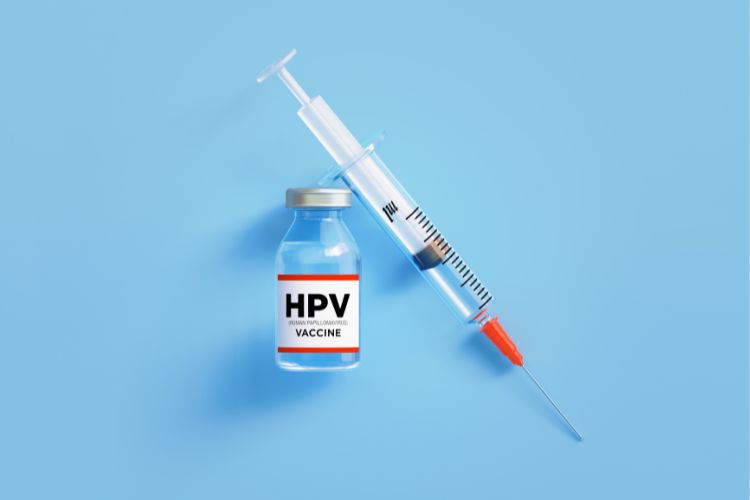 Hpv-Vacina Fundo azul com frasco de vacina escrito "HPV vaccine" e seringa com agulha