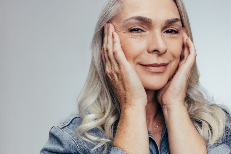 Resveratrol-Pele Mulher mais velha, de cabelos brancos, esticando levemente a pele do rosto