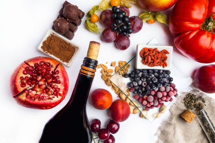 Resveratrol-Frutas-Vinho Foto de futas como uva, mirtilo, romã, além de garrafa de vinho tinto e cacau